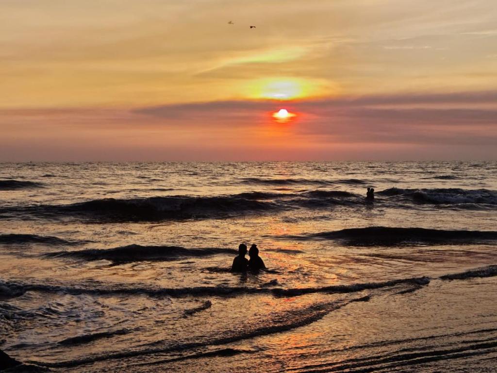 Due persone sedute in acqua al tramonto sulla spiaggia di Posada Playa Linda a Ixtapa