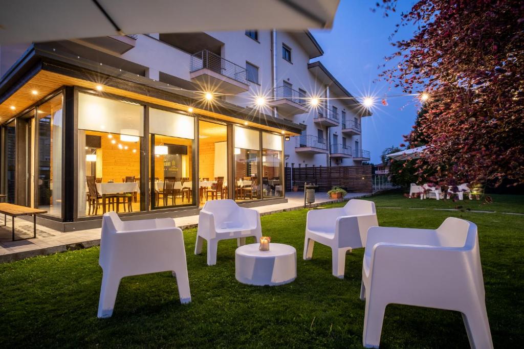 une cour avec des chaises et des tables blanches et un bâtiment dans l'établissement Draconerium Hotel, à Dronero