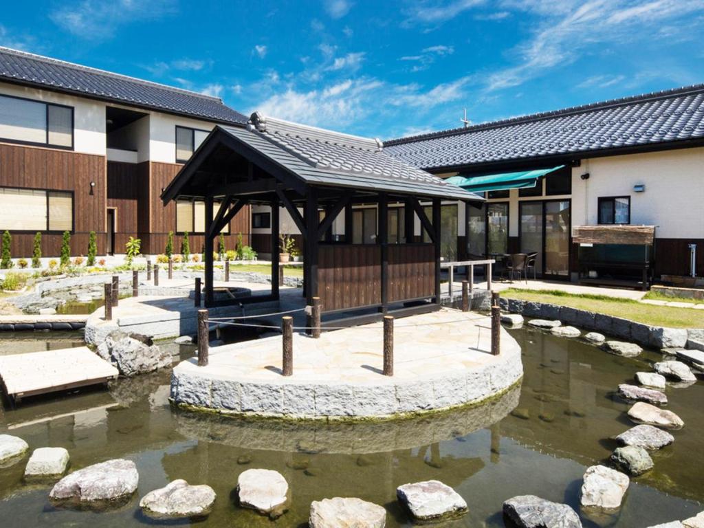 a building with a gazebo next to a pond at Racine Home Harie in Takashima