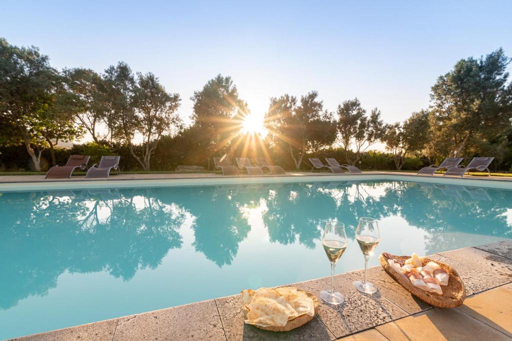 una piscina con dos copas de vino y una cesta de comida en Agriturismo Casa Marmida, en Pardu Atzei