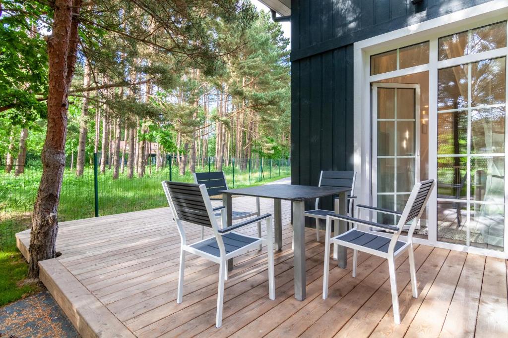 a wooden deck with a table and chairs on it at Karklė Living Apartments, By Cohost in Karklė