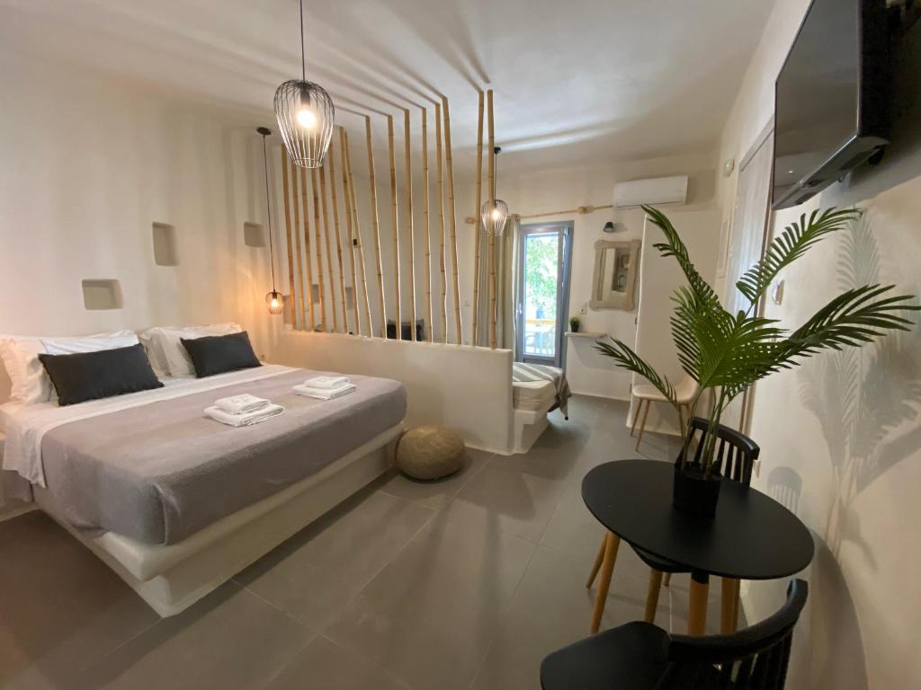 ナクソス・コラにあるAmpelos Suitesの白いベッドルーム(大型ベッド1台、テーブル付)