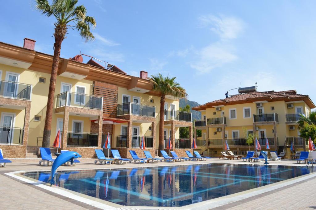 a resort with a swimming pool with chairs and palm trees at Yalcin Hotel & Villas in Oludeniz