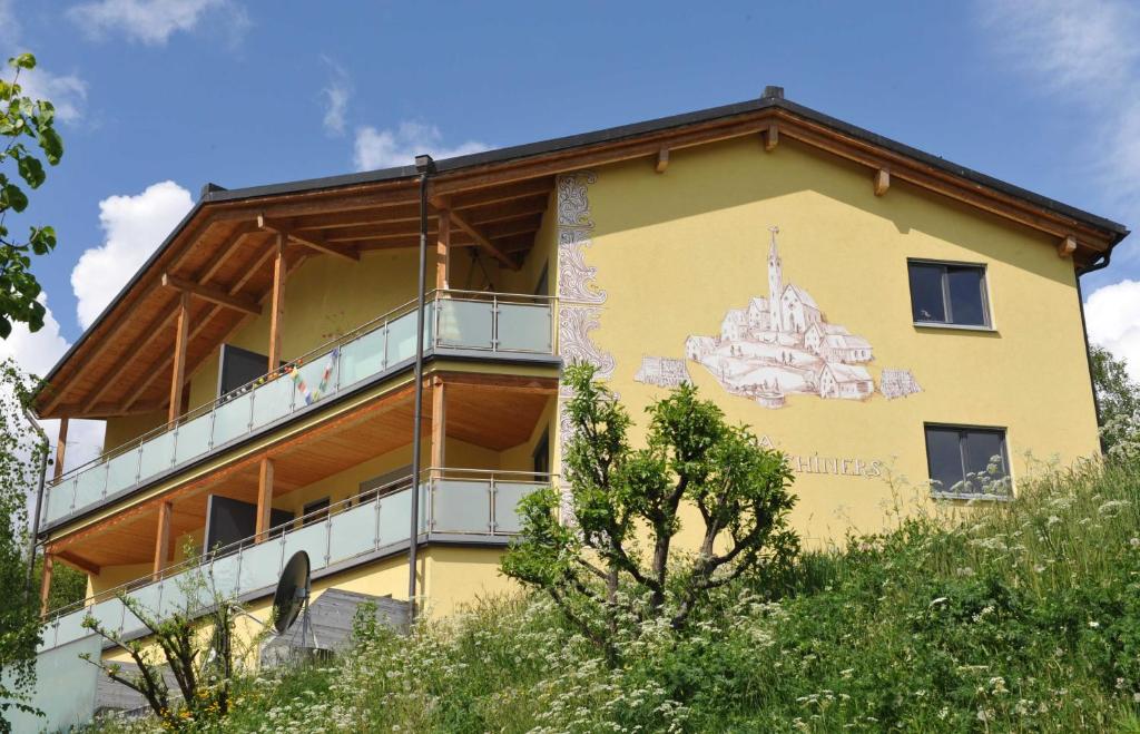 ein gelbes Gebäude mit einem Gemälde auf der Seite in der Unterkunft Buorcha in Scuol