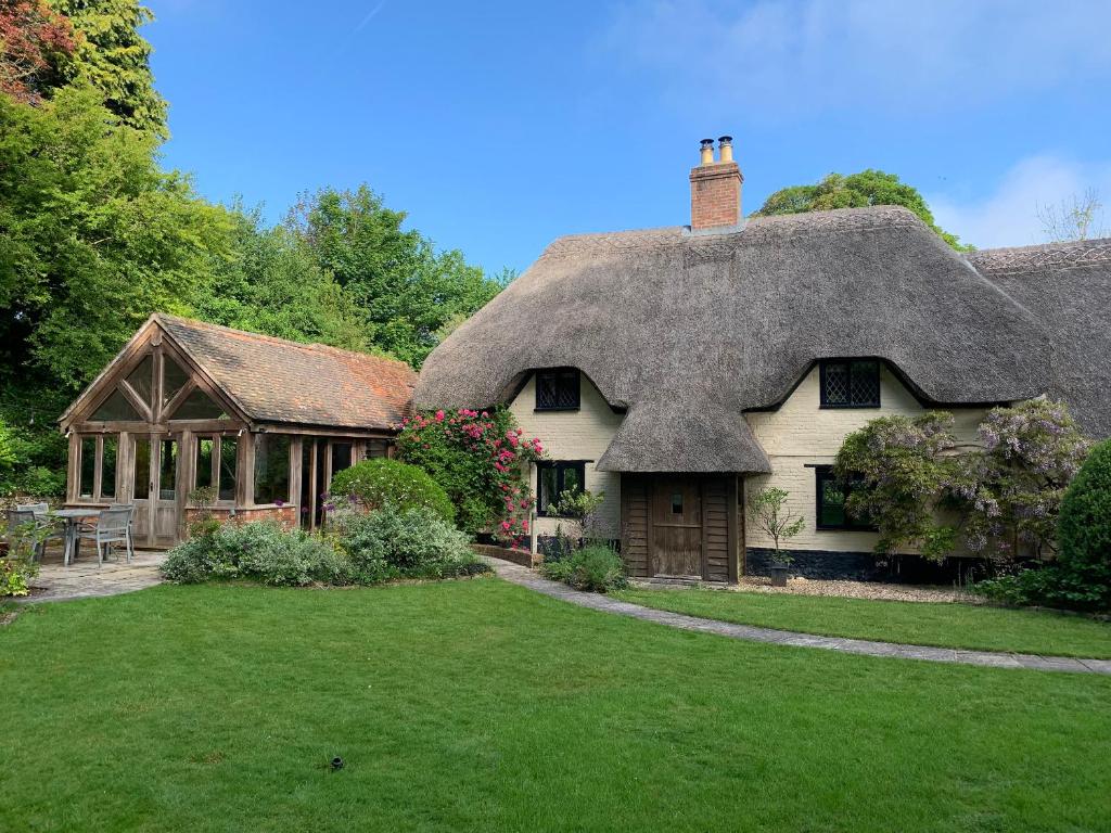 a thatch roofed house with a porch at Under Acre Cottage in Blandford Forum