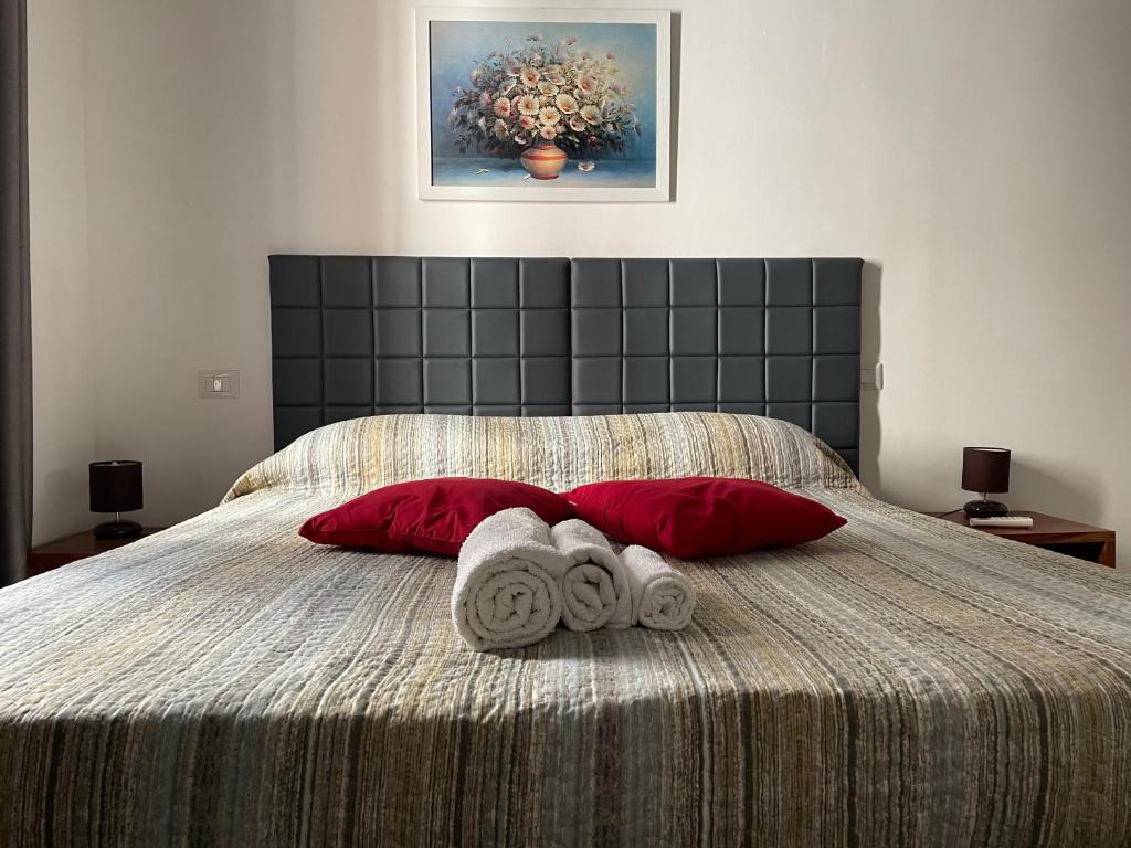 1 cama con 2 almohadas rojas y 2 toallas en Saturno house Cagliari Center, en Cagliari