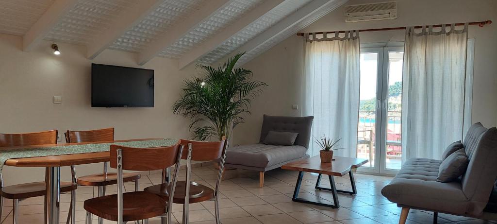 een woonkamer met een tafel en stoelen en een televisie bij Pension Alexandra in Parga