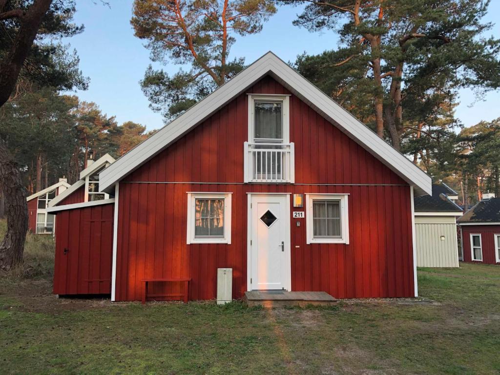 a red barn with a white door and windows at Ferienhaus Sprottenkiste in Baabe