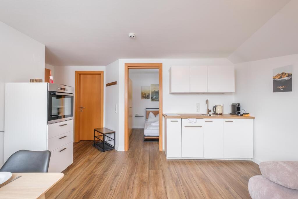 Il comprend une cuisine avec des placards blancs et du parquet. dans l'établissement Alpen Apartment + Sauna und Netflix, à Piesendorf