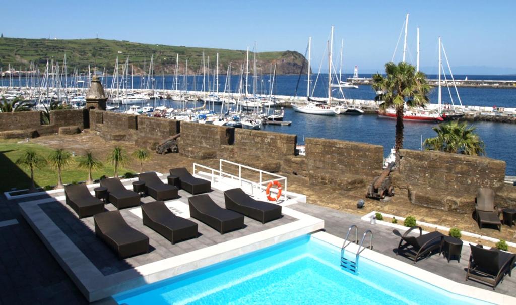 a swimming pool with lounge chairs and a marina at Pousada Forte Horta in Horta