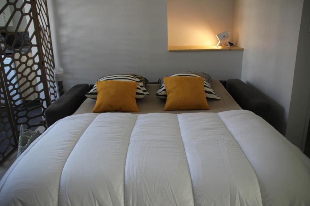 a large white bed with two yellow pillows on it at Centre ville à pied Appt avec SAUNA, Linge, Wifi, Stationnement Gratuit in Vannes