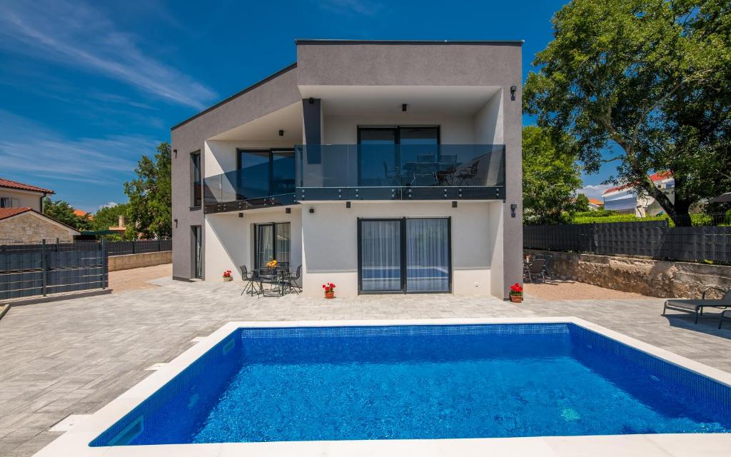 une villa avec une piscine en face d'une maison dans l'établissement Apartments Villa "Aurea" with pool, à Krk