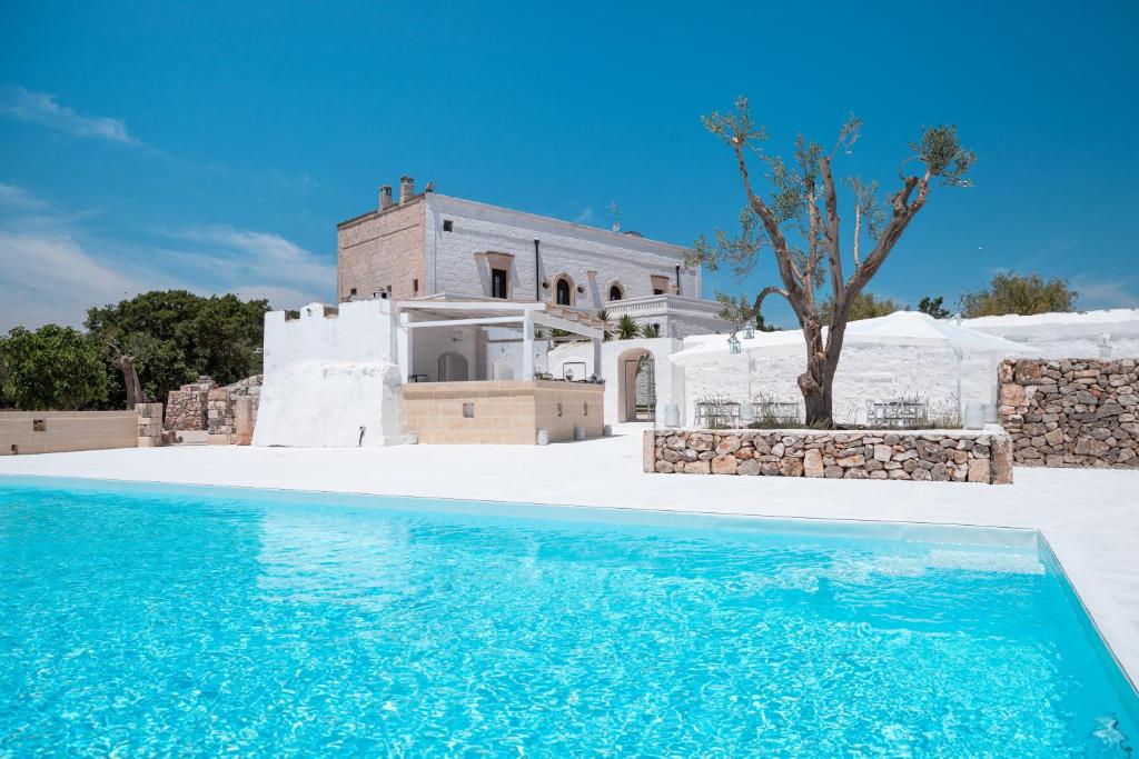 a villa with a swimming pool in front of a house at Masseria Donna Nina in Ostuni