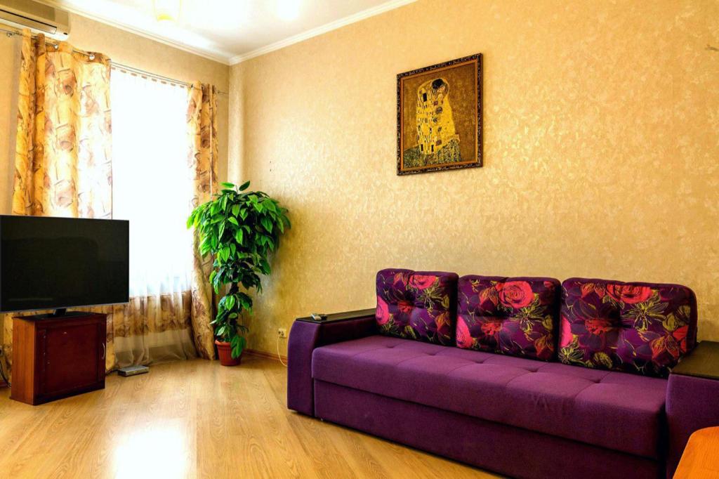 un salon avec un canapé violet et une télévision dans l'établissement Large apartment in the center, à Dnipro
