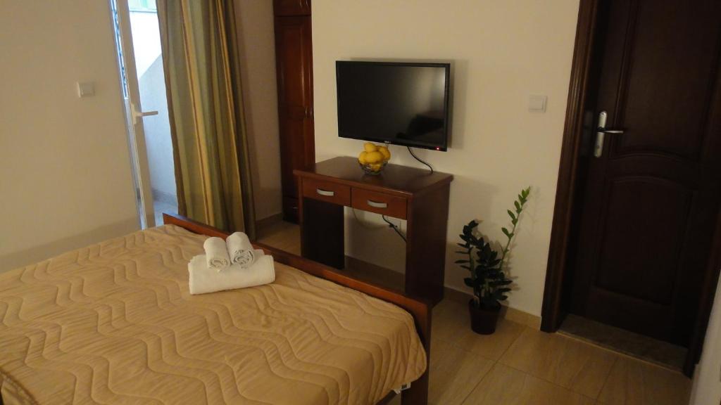 a hotel room with a bed and a flat screen tv at Apartmani More in Sveti Stefan