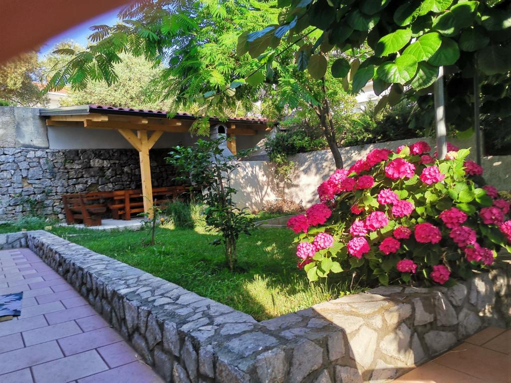 a garden with pink flowers and a stone wall at Apartments Jessica in Krk