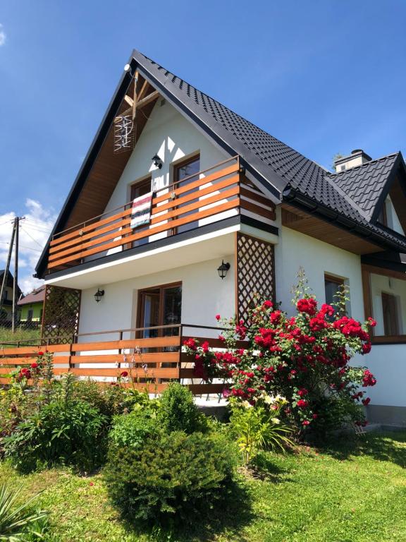 uma casa com flores vermelhas em frente em Domek Letniskowy em Zubrzyca Dolna