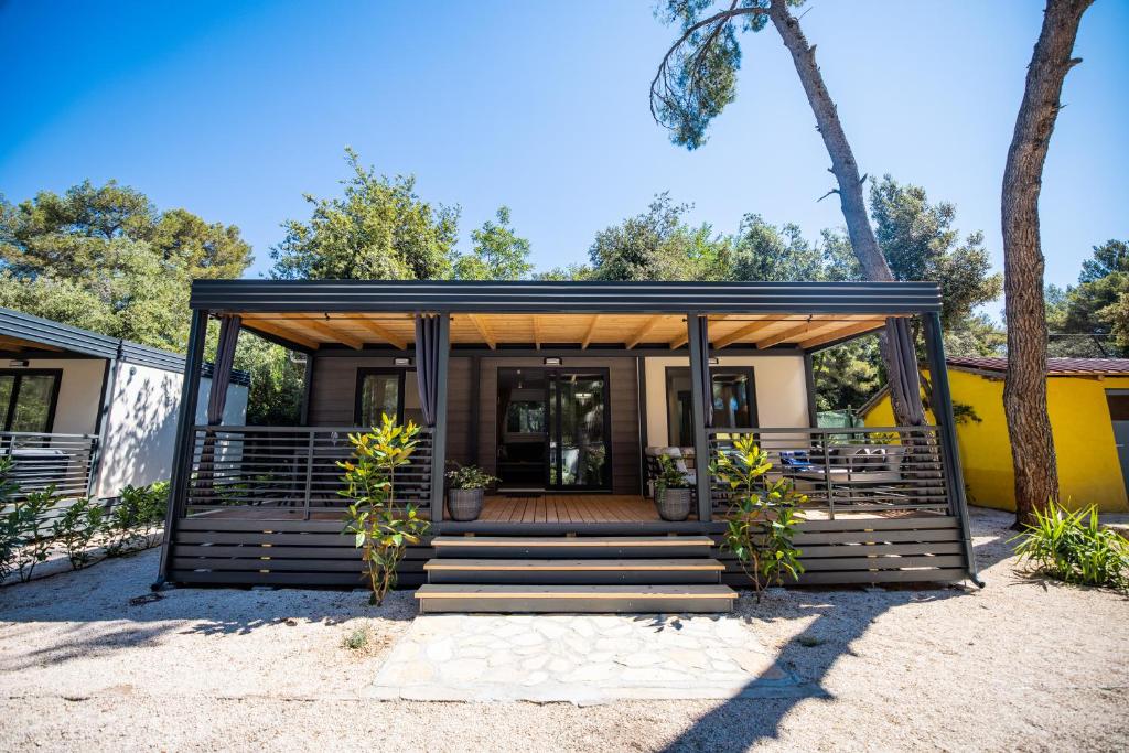 een tiny house met een veranda en een trap bij Mobile Homes Ljutić in Biograd na Moru