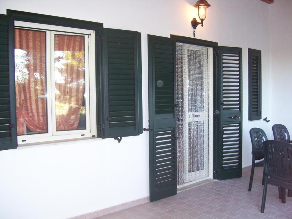 a room with two windows with green shutters at Althea Village Residence in Vieste