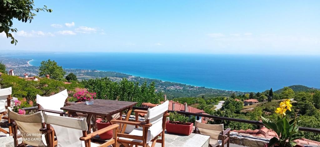 balcón con mesa, sillas y vistas al océano en Enastron Guesthouse, en Palaios Panteleimon
