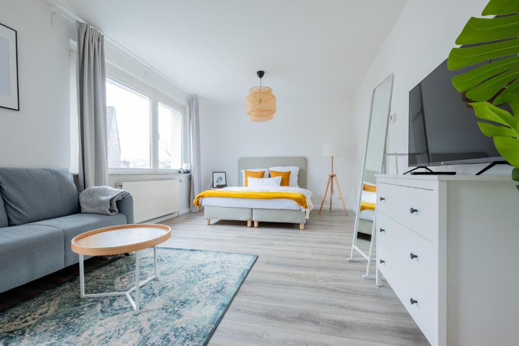 - un salon blanc avec un lit et une télévision dans l'établissement Ferienwohnung res publica, à Wuppertal