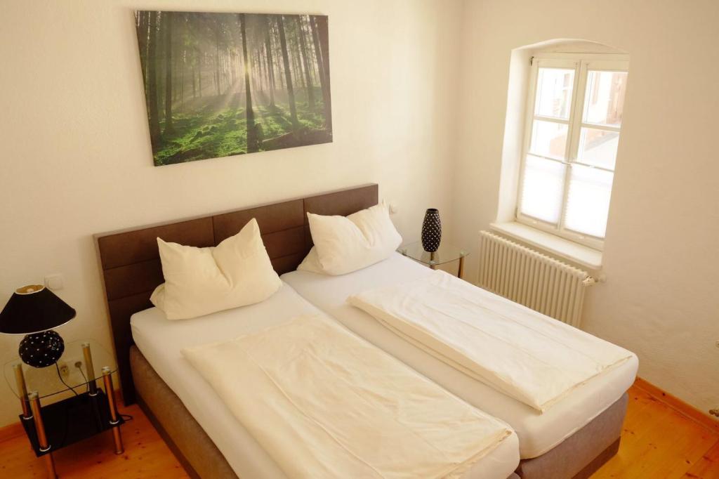Una cama con sábanas blancas y almohadas en un dormitorio en Ambiente Ferienwohnungen, en Sankt Martin