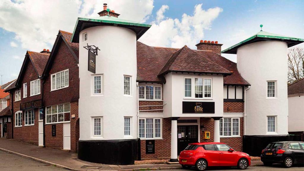 un coche rojo estacionado frente a un edificio blanco en The Old Castle Hotel en Rodwell