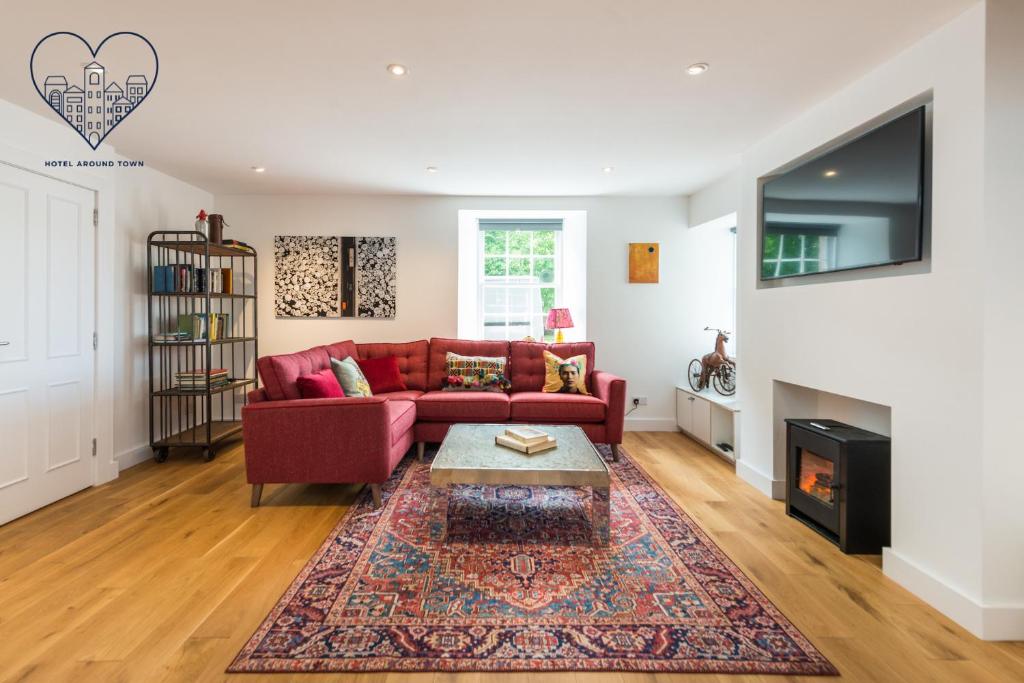 a living room with a red couch and a fireplace at Charming 3 Bed Village Green Cottage East Lothian in Gifford