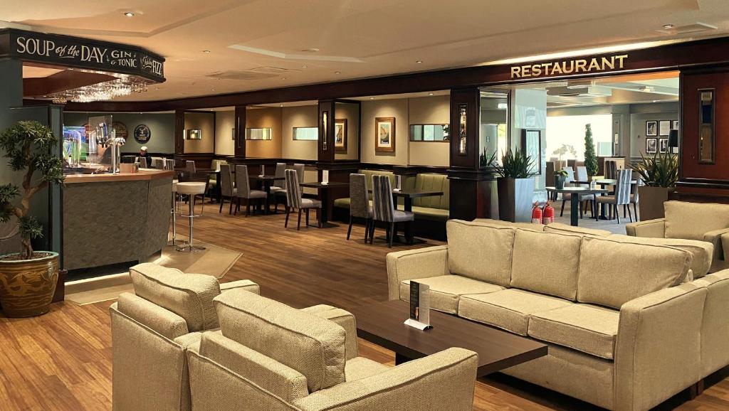 a lobby with couches and tables and a restaurant at Normandy Hotel (Near Glasgow Airport) in Paisley