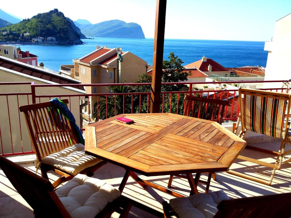 d'une table et de chaises en bois sur un balcon donnant sur l'océan. dans l'établissement Apartments Almaja Villa, à Petrovac na Moru