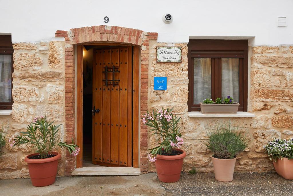 een gebouw met een houten deur en potplanten bij La Pequeña Luz Casa Rural in Tabanera de Cerrato