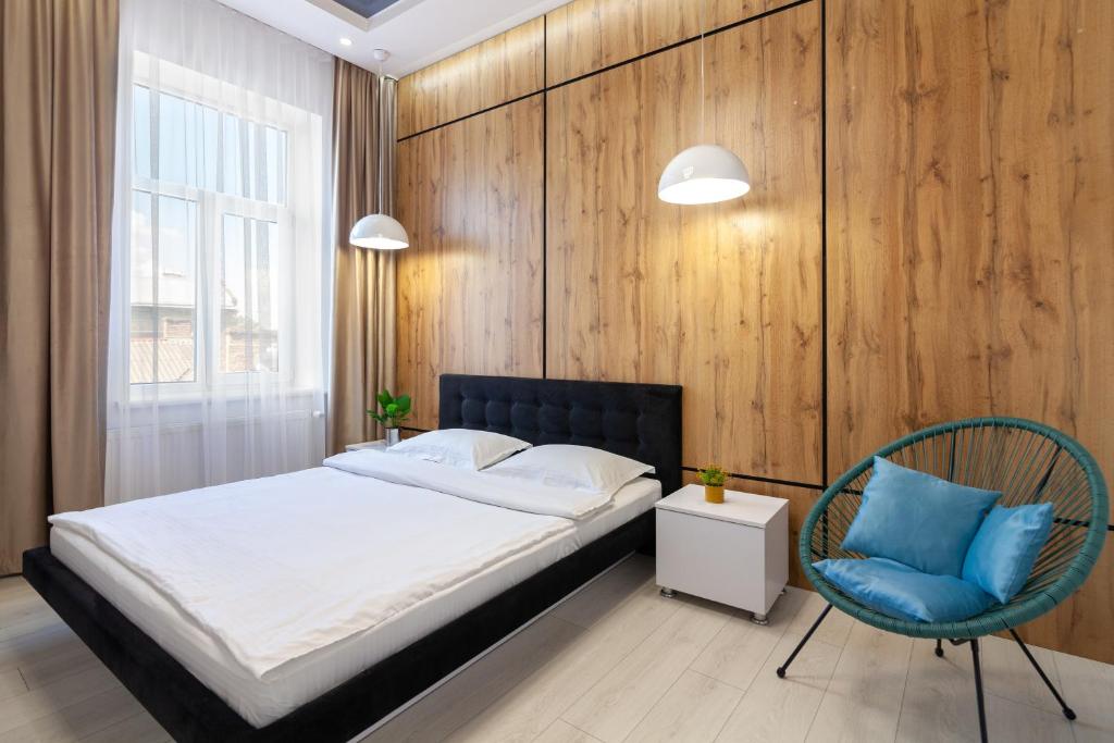 a bedroom with a bed and a blue chair at LEOGRAND VIP Apartments on Pidhirna 3 in Lviv