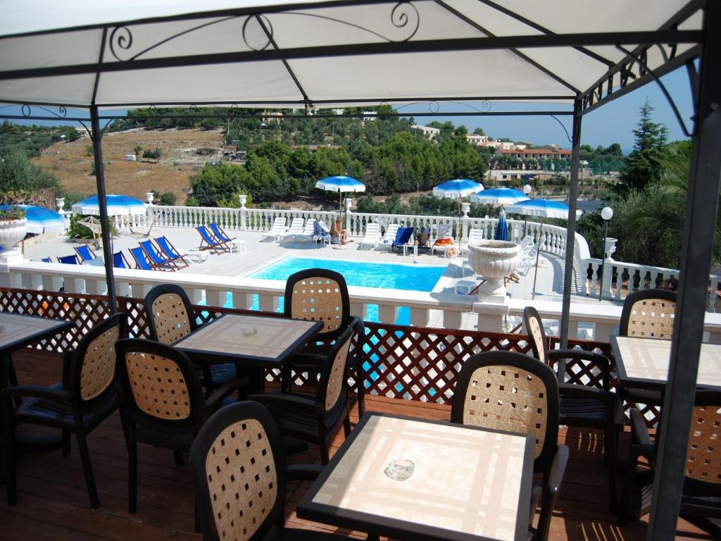 a patio with tables and chairs and a swimming pool at Althea Village Residence in Vieste