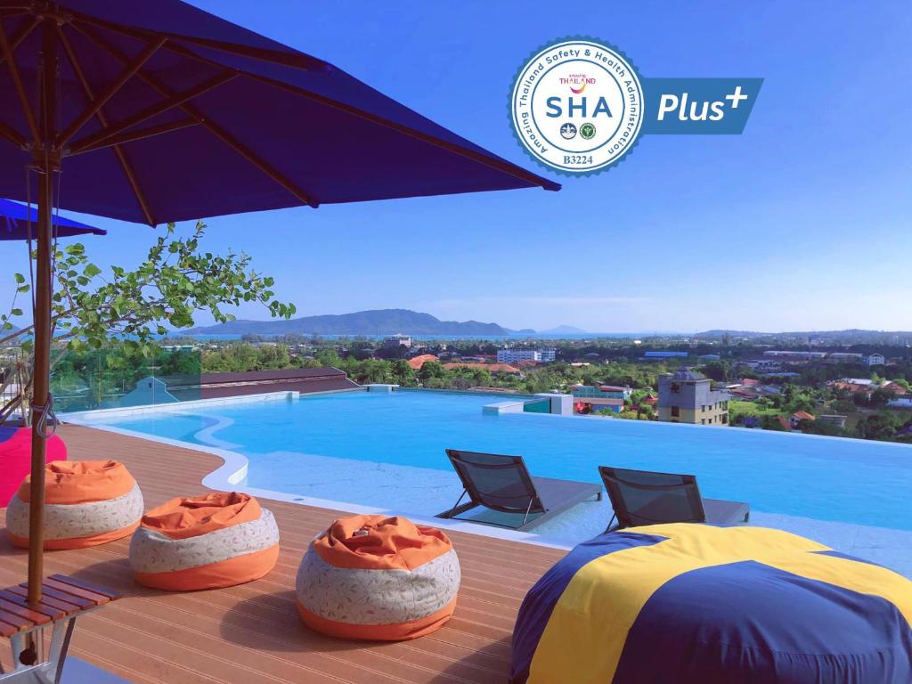 a pool with two tables and an umbrella on a deck at The Blue Hotel - SHA Plus in Chalong 
