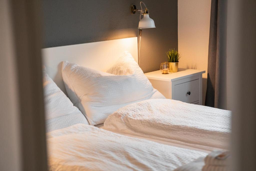 um quarto com uma cama com lençóis brancos e almofadas em KALCHOFEN Restaurant Hotel Eventhouse em Hasle