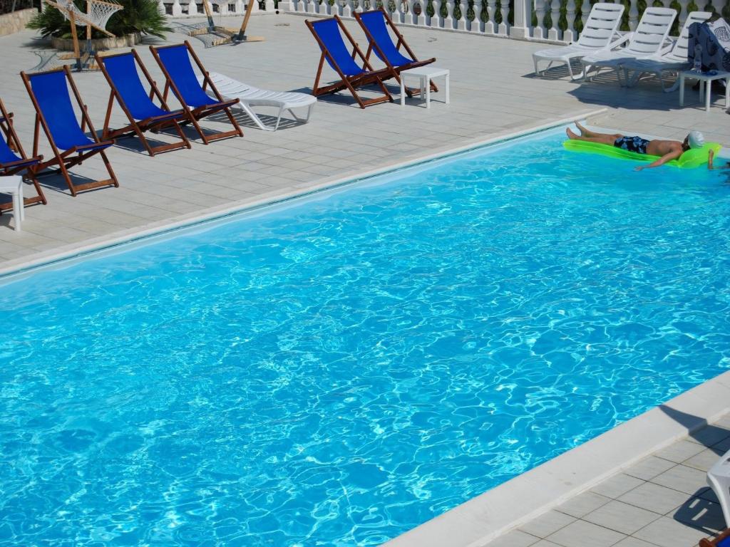 a person laying on a raft in a swimming pool at Althea Village Residence in Vieste
