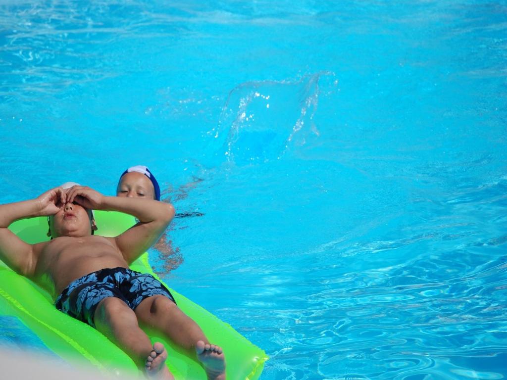 two children laying on a raft in the water at Althea Village Residence in Vieste