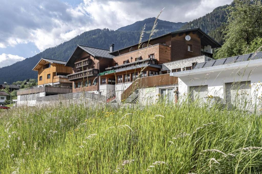 a large building in the middle of a field of grass at Hotel Vallüla in Sankt Gallenkirch