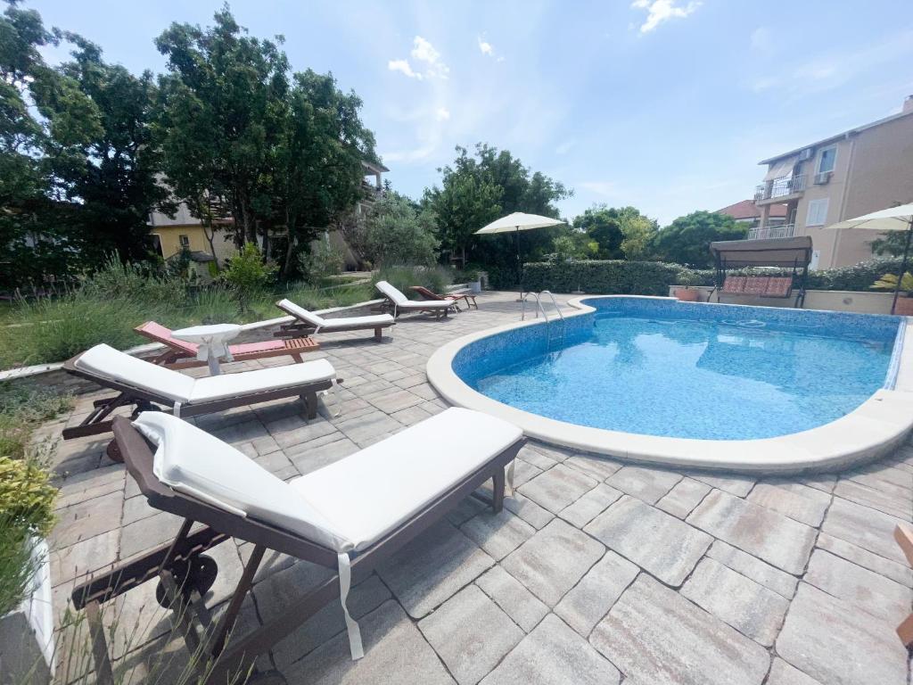 a swimming pool with chaise lounge chairs and a swimming pool at Apartmani Matković in Jadranovo