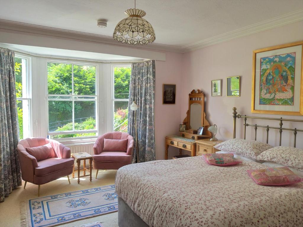 a bedroom with a bed and two chairs and a window at Cascades Gardens in Matlock