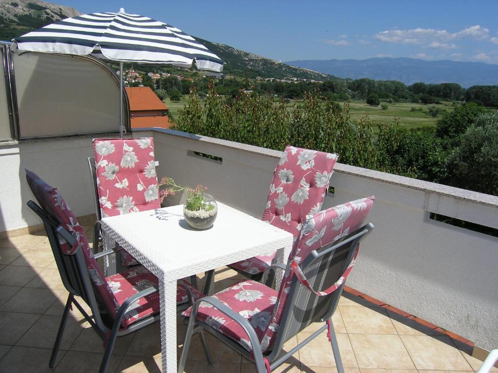 einen Tisch und Stühle auf einem Balkon mit Sonnenschirm in der Unterkunft Apartments Jadranka with magnificent views of the sea - Baska in Baška