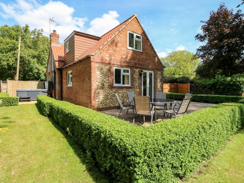 a brick house with a garden and a table and chairs at Keepers Cottage in Beeston