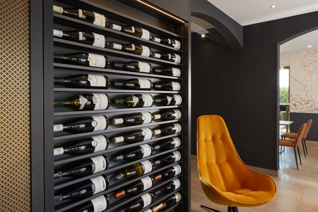 ボーヌにあるMaison Cabotteのワインセラーのワインボトルの壁(黄色い椅子付)