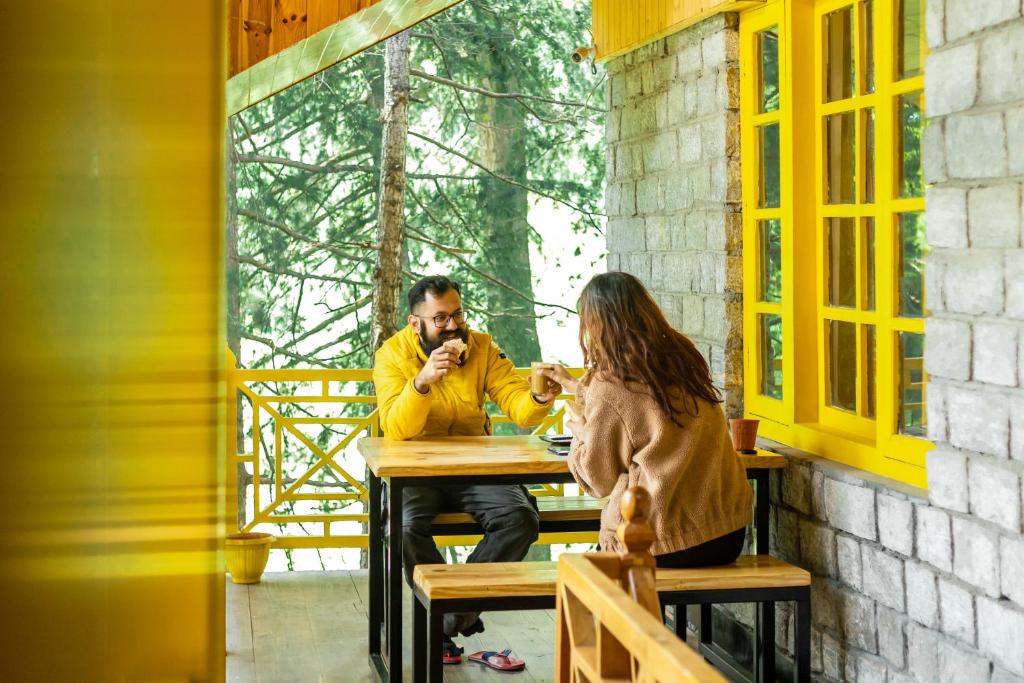 Un uomo e una donna seduti a un tavolo su un portico di The Hosteller Manali a Manāli