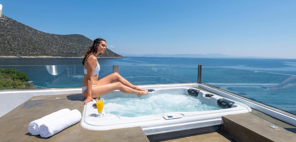 una mujer sentada en un jacuzzi en la parte superior de una casa en Paraskevas Boutique Hotel, en Tyros