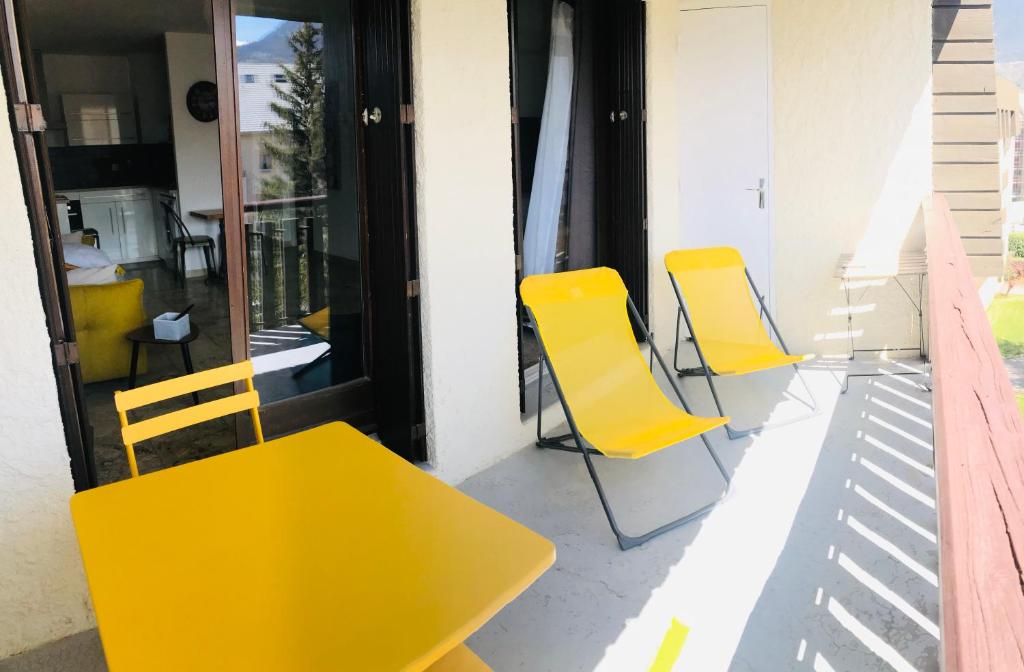 昂布朗的住宿－les saluces N51，阳台上配有3把黄色椅子和一张桌子