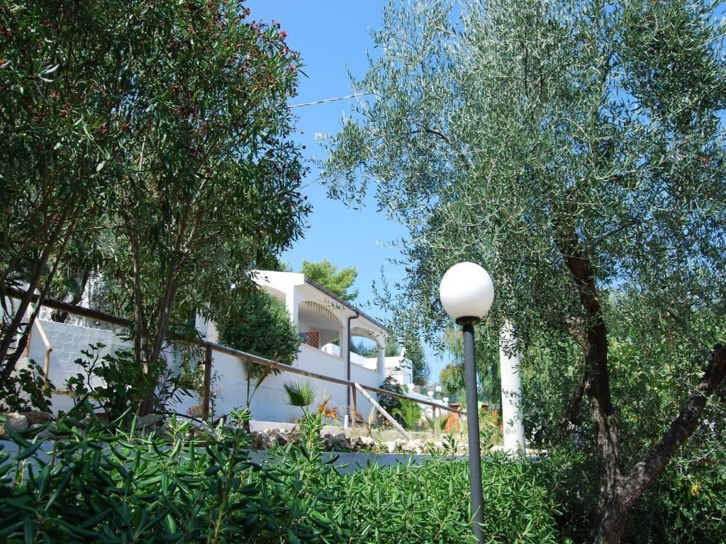 a white house with trees and a street light at Althea Village Residence in Vieste