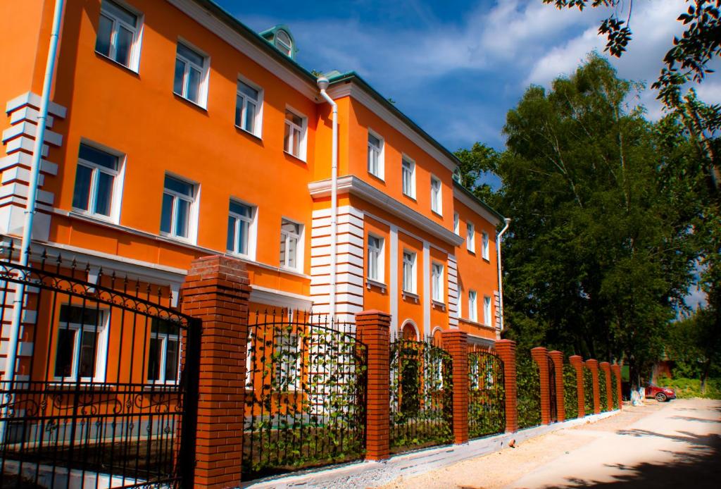 an orange building with a fence in front of it at Orange House Hotel in Moscow