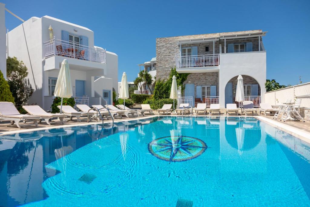 a swimming pool with chairs and a building at Katerina Hotel in Agios Prokopios