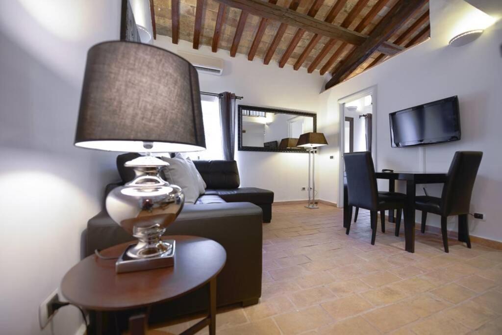a living room with a couch and a table with a lamp at Ibernesi - Charming apartment at the Roman Forums in Rome